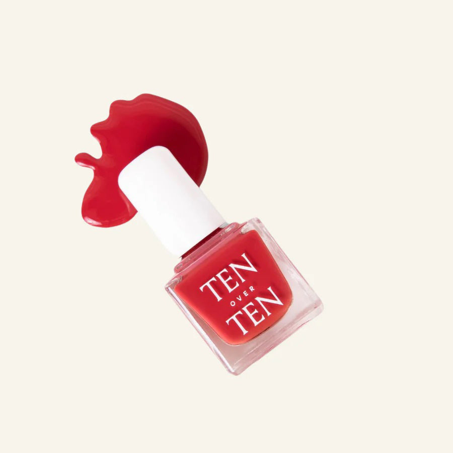 A glass bottle of TENOVERTEN - NAIL POLISH from the brand TEN OVER TEN, featuring a white cap and a dusty pink nail color. The front label displays "TEN OVER TEN" in white uppercase letters. This vegan, eight-free formula ensures both beauty and peace of mind. The background is plain and light-colored.