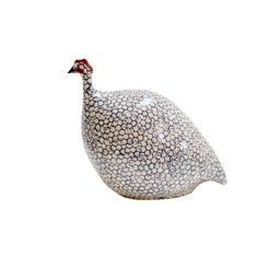 The LES CERAMIQUES DE LUSSAN - MEDIUM FRENCH GUINEA IN BLUE SPOTTED COBALT is a handmade ceramic sculpture featuring an intricate speckled pattern and distinctive red head detail. The predominantly white rounded body, adorned with black circular designs, echoes the appearance of guinea hens. Its plain white background highlights the artisanal charm of LES CERAMIQUES DE LUSSAN&#39;s craftsmanship.
