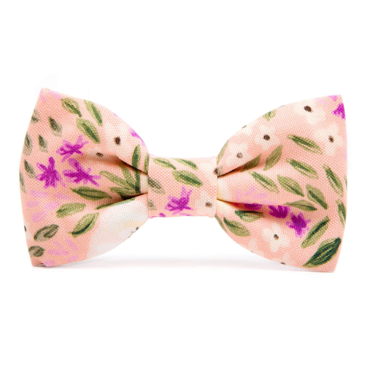 The Foggy Dog&#39;s standard Harper Floral dog bow tie features a pink base adorned with green leaves, ivory and purple flowers, and small black dots. The soft-textured fabric along with its delicate color palette evokes a spring-like feel.