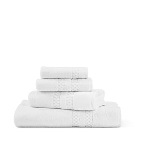 A set of four neatly stacked towels from the FEARRINGTON LIFESTYLE TOWEL COLLECTION by Frette North America is displayed against a plain white background. These luxurious white cotton bath towels are adorned with a textured band across the width, adding an elegant design element to the plush linens.