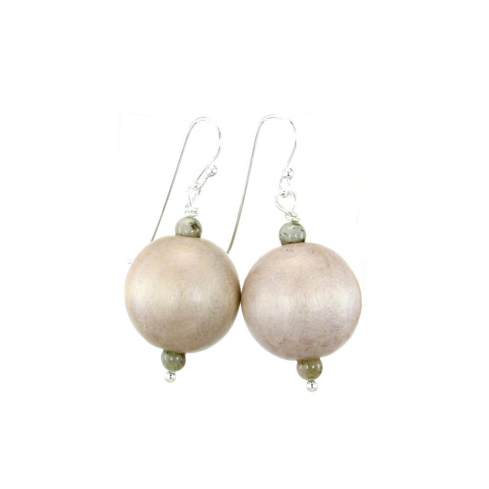 The ANN LIGHTFOOT - GREY WOOD DROP EARRING features large, round light beige beads as the main attraction. Each earring includes two smaller light grey wood beads above and below the central bead. The beads are elegantly attached to a sterling silver earwire, all set against a plain white background.