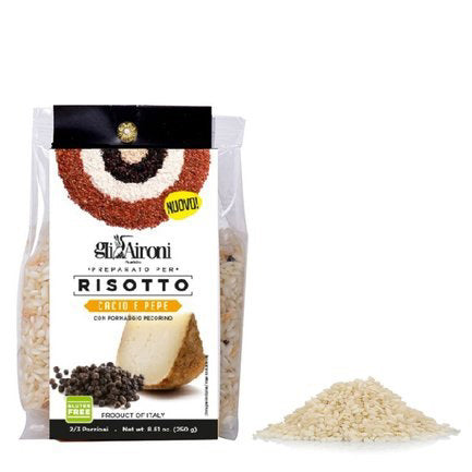 A package of GLI AIRONI - CACIO E PEPPE RISOTTO by ZIA PIA IMPORTS is placed against a white background. The package shows an image of ready-to-cook cacio e pepe risotto garnished with cheese and black pepper. Next to the package, there is a small mound of uncooked carnaroli rice.