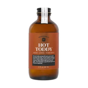 An 8 fl oz (237 ml) brown glass bottle labeled "YES COCKTAIL CO - HOT TODDY SYRUP" from YES COCKTAIL CO., featuring the description "Honey, Lemon, Warm Spice" below. The label promises a warming seasonal drink, perfect for cozy winter nights.