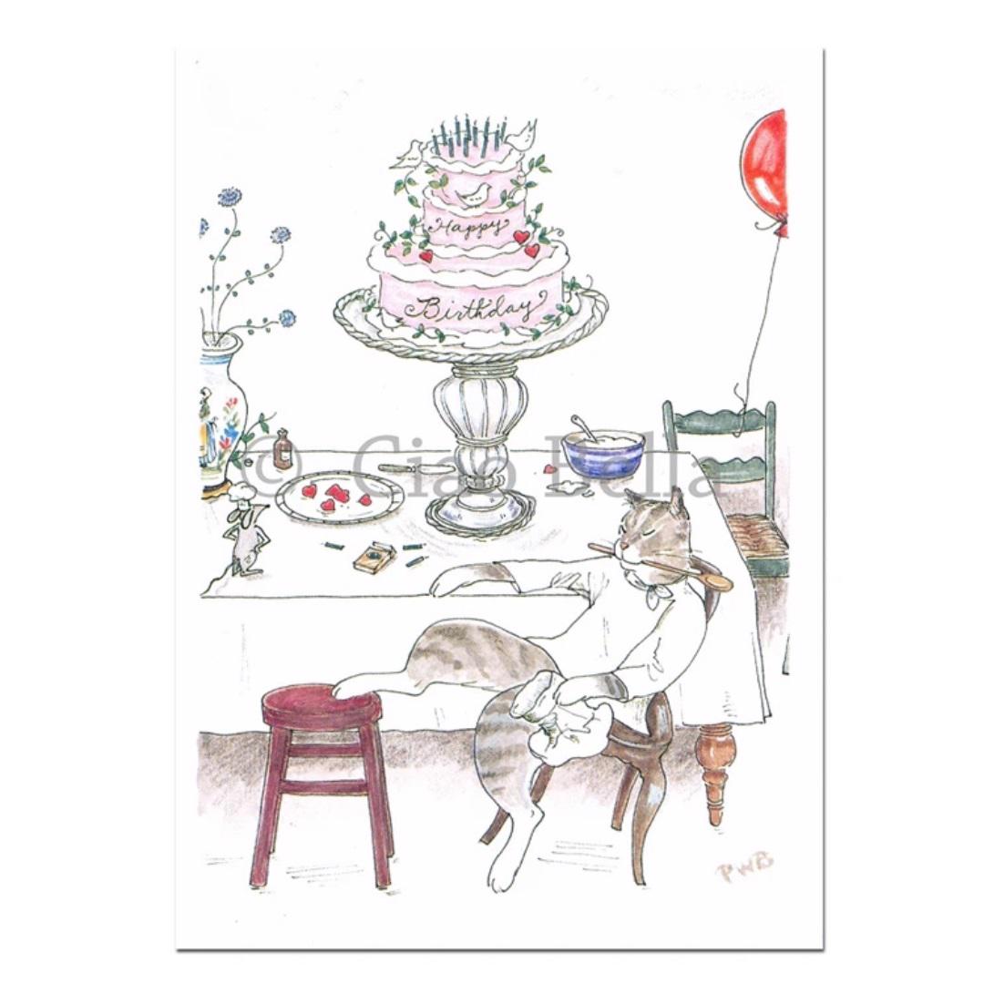 The CIAO BELLA - TINKER'S CAKE CARD features a whimsical illustration of a cat wearing a pink dress, sitting on a chair with its legs crossed. It is positioned next to a table adorned with a large, decorated birthday cake on a pedestal. The table also includes a small bowl, red berries, utensils, an envelope, and a blank note card. Nearby floats a single red balloon.