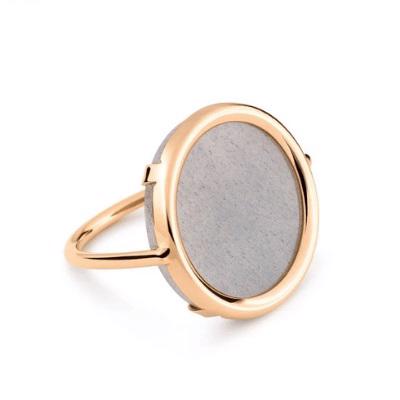 The EVER MOONSTONE 18K ROSE GOLD (7) by GINETTE NY is a minimalist ring featuring a large, round face with a smooth, light gray stone. The elegant design includes a thin, polished band that curves outward to secure the stone in place, embodying the modern aesthetic characteristic of DISC RINGS.