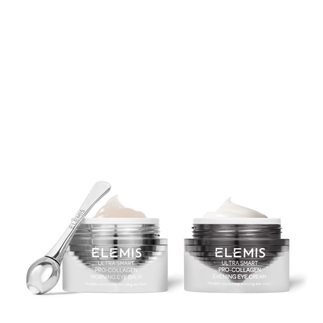 The image shows two silver and white jars from the ELEMIS - STEINER brand&#39;s Pro-Collagen Ultra Smart Collagen Eye Treatment Duo. The left jar is labeled &quot;Morning Eye Balm&quot; for dark circles, while the right jar is labeled &quot;Evening Eye Cream&quot; with anti-aging benefits. A small, silver applicator tool is placed next to the jars.
