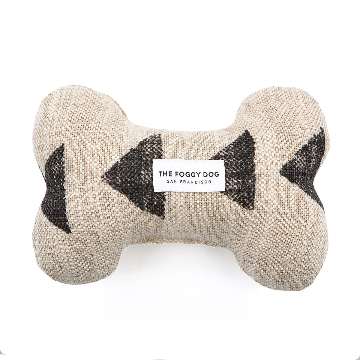 Introducing our DOG BONE SQUEAKY TOY (AMANI SAND) by THE FOGGY DOG: a beige, bone-shaped dog toy adorned with black inward-pointing arrow patterns on both sides. This handcrafted piece from our pet products collection features eco-friendly fiberfill and proudly displays a white label at the center that reads &quot;THE FOGGY DOG SAN FRANCISCO.