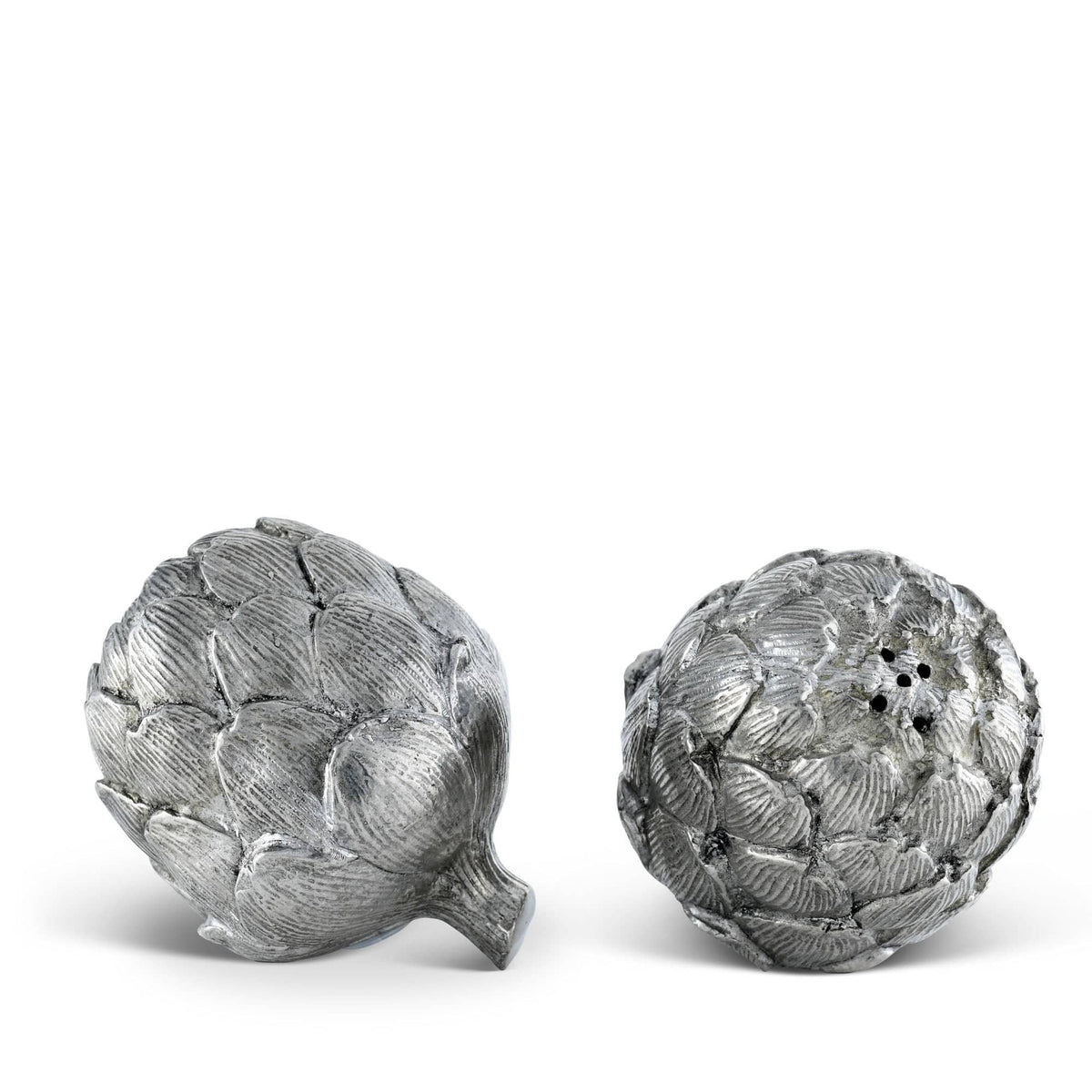 The VAGABOND HOUSE PEWTER ARTICHOKE SALT AND PEPPER SET includes two luxury-grade pewter pieces with realistic textured leaves and top holes, one upright and the other on its side, elegantly displayed on a plain white background.