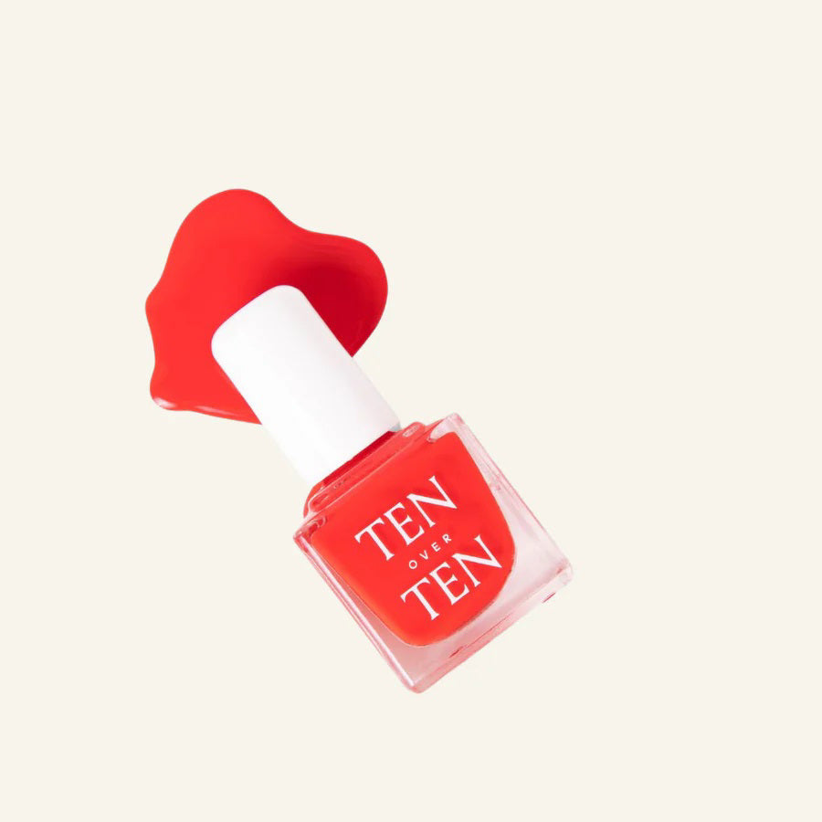 A glass bottle of TENOVERTEN - NAIL POLISH from the brand TEN OVER TEN, featuring a white cap and a dusty pink nail color. The front label displays "TEN OVER TEN" in white uppercase letters. This vegan, eight-free formula ensures both beauty and peace of mind. The background is plain and light-colored.