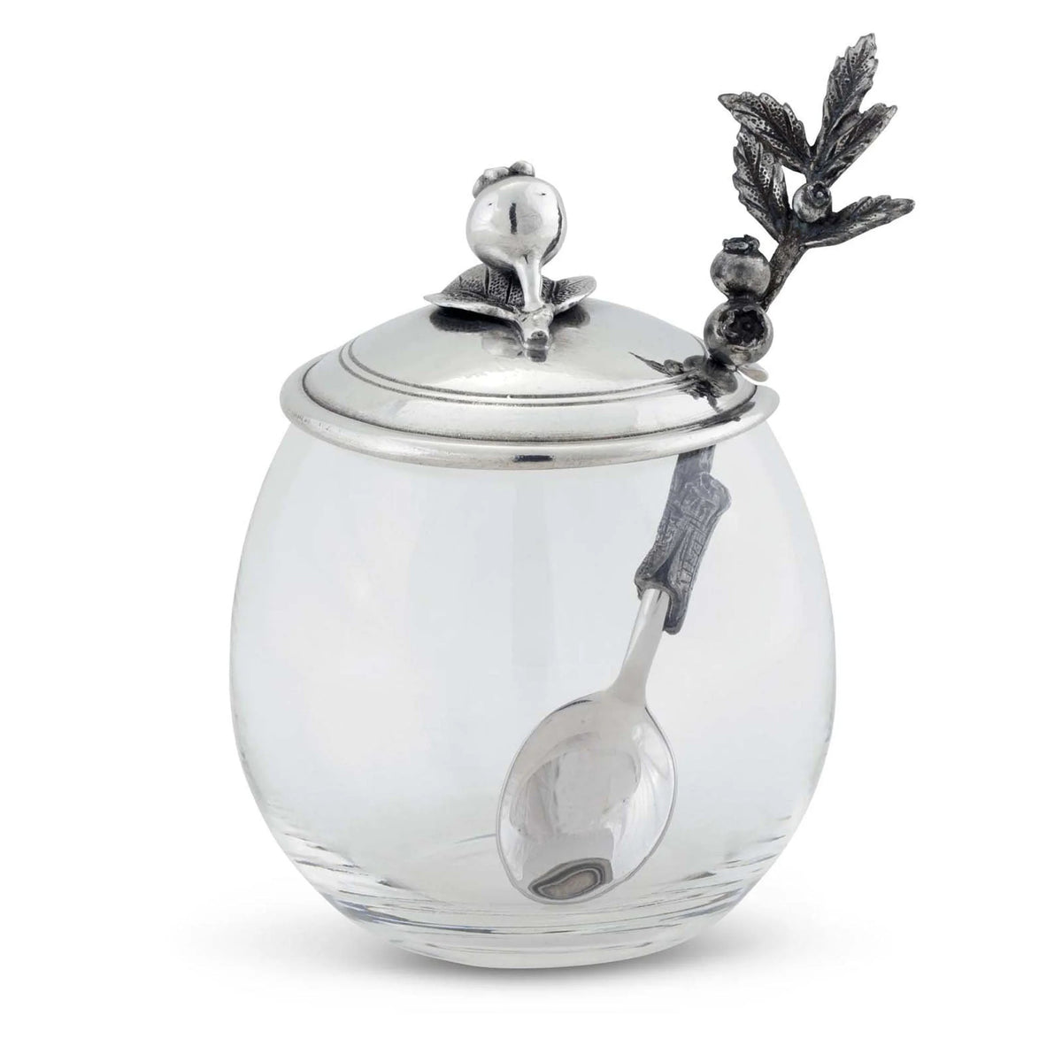 The VAGABOND HOUSE BLUEBERRY JAM JAR features a clear glass body with a silver lid adorned with intricate pewter birds and leaves, paired with a spoon that has a branch-like handle, offering elegance by the brand VAGABOND HOUSE.