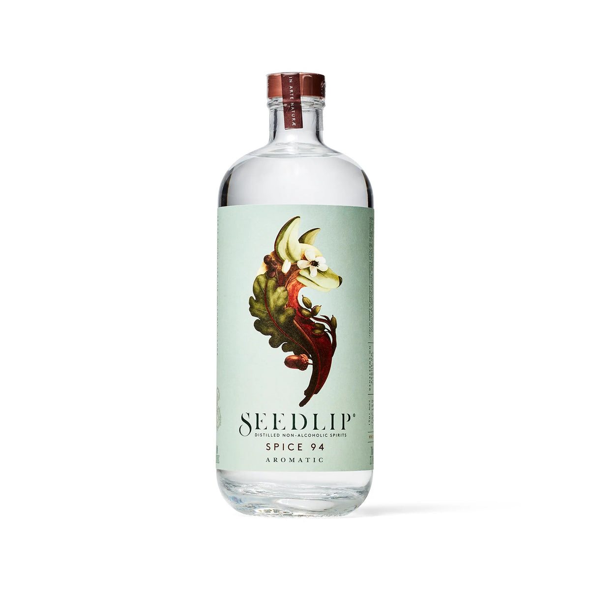 A clear bottle of SEEDLIP - SPICE 94 NON ALCOHOLIC SPIRIT by SEEDLIP DRINKS, featuring a light green label with leaves and spices, plus a copper-colored cap, displayed against a white background.