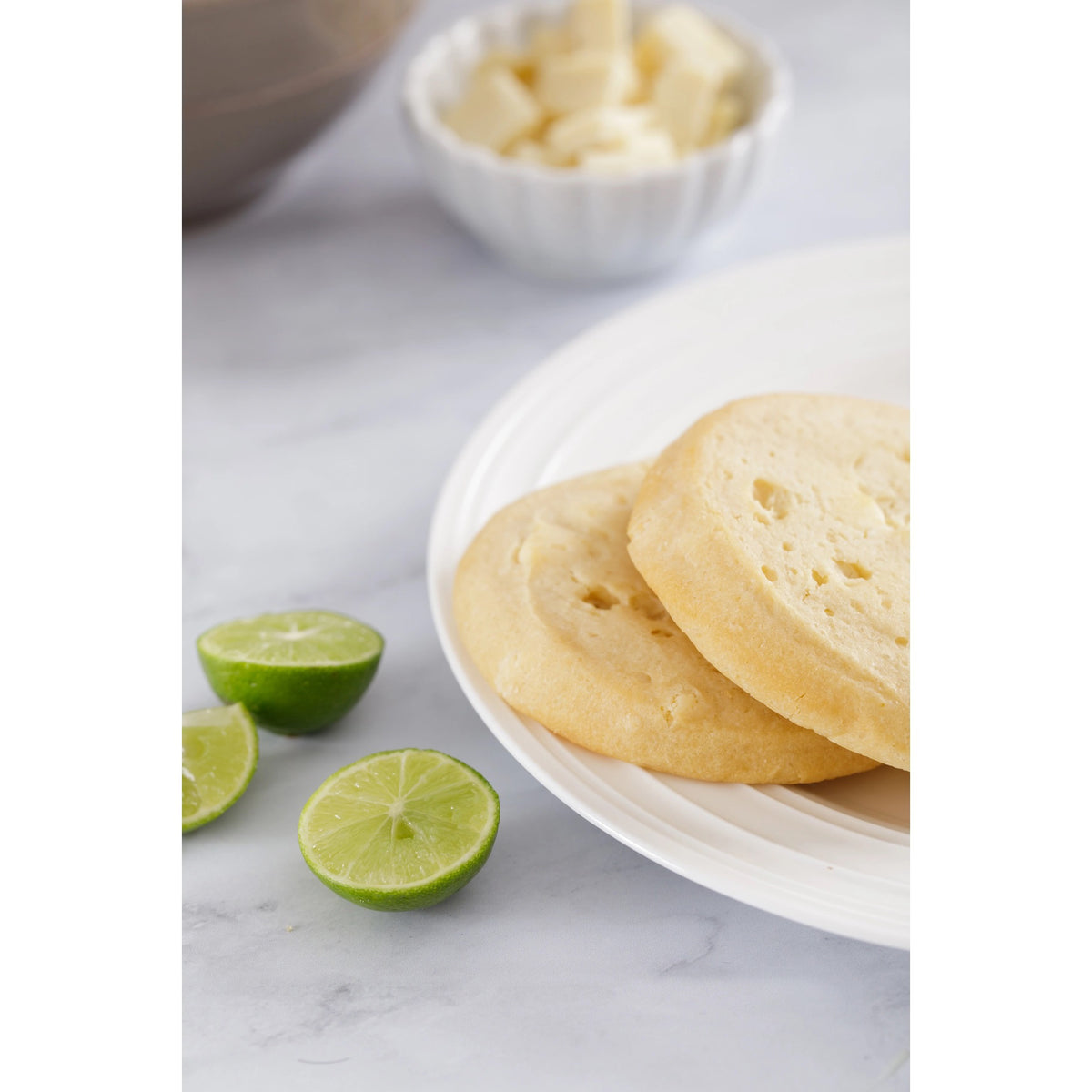 A packet of WOW Baking Company's Gluten-Free Key Lime White Chocolate Cookies. The packaging features a prominent "WOW" logo, mentions "made with natural ingredients" and "GMO free." Text at the top highlights that the product is wheat and gluten-free.