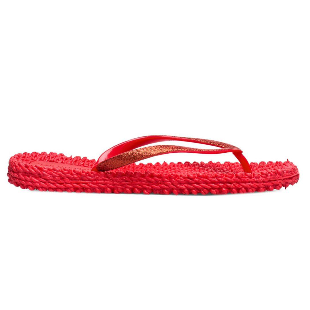 The ILSE JACOBSEN CHEERFUL FLIP FLOP IN DEEP RED by LINES OF DENMARK features vibrant red sandals with textured soles, glitter straps, and a comfortable fit, elegantly placed on a plain white surface.