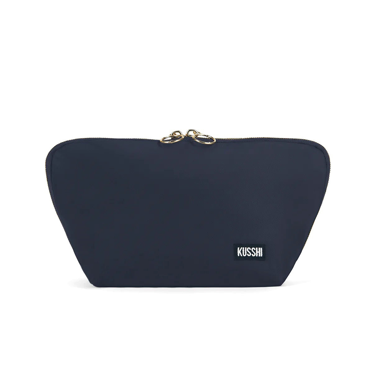 The KUSSHI Signature Makeup Bag in Navy features a minimalist design with a slightly triangular shape. This navy blue zipped pouch includes a black rectangular label with white text that reads &quot;KUSSHI&quot; near the bottom right corner and two golden pull tabs at the top center. Additionally, this makeup bag is machine washable.