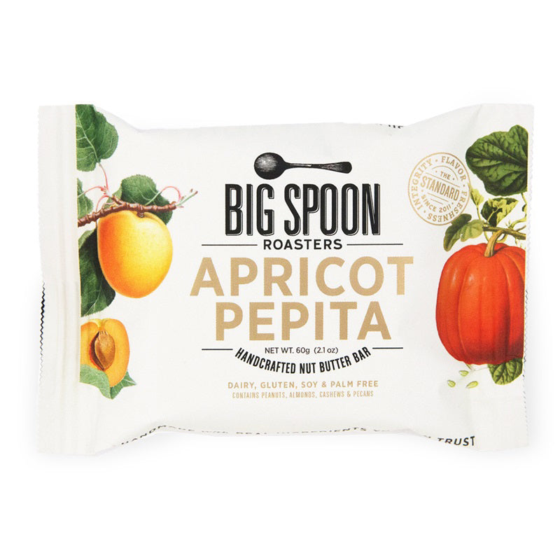 A rectangular white packet labeled "BIG SPOON ROASTERS - APRICOT PEPITA PEANUT SNACK BAR," decorated with images of apricots and pepitas. The packaging highlights that it's a handcrafted nut butter bar containing non-GMO pea protein, and is free from dairy, gluten, soy, and palm oil. The net weight is 60 grams (2.1 oz).