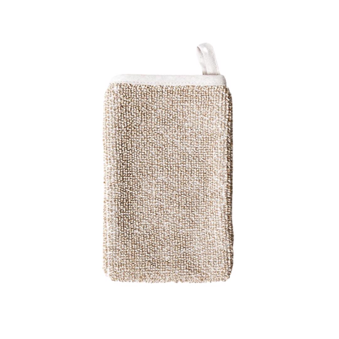 The SASAWASHI DEEP EXFOLIATING BODY SCRUB MITT by MORIHATA is a rectangular mitten crafted from textured, rough Sasawashi fabric in a beige color. It features a white fabric loop at the top for convenient hanging. Its texture makes it perfect for deep exfoliation during bathing or showering.