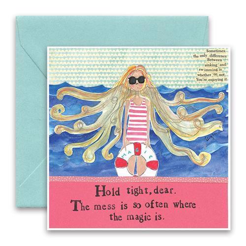 The CURLY GIRL DESIGNS - MESS GREETING CARD by CURLY GIRL DESIGN, INC showcases a colorful collage art featuring an illustration of a person with flowing blonde hair, wearing sunglasses and sitting on a life preserver in the water. The card includes the text, "Hold tight, dear. The mess is so often where the magic is," and comes with an envelope in the background.