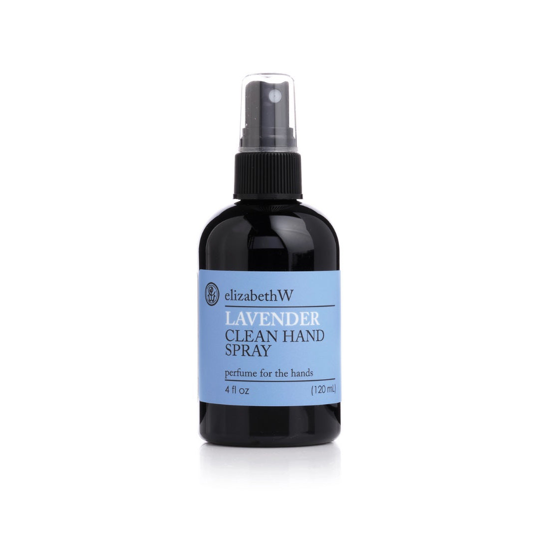 A 120 ml (4 oz) black bottle of LAVENDER HAND SPRAY 4OZ by E WIGHTMAN & CO is shown. The bottle has a spray nozzle cap and a light blue label that reads "elizabethW Lavender Clean Hand Spray," featuring lavender essential oil and 70% alcohol for effective cleaning.