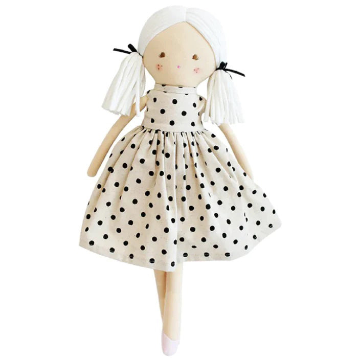 Introducing the ALIMROSE - FRANKIE DOLL BLACK LINEN SPOT from ALIMROSE: a charming cloth doll with white yarn hair styled in pigtails, tied with black ribbons. This Dress Up Doll is elegantly dressed in a sleeveless, cream-colored dress adorned with black polka dots and features pink blush on its cheeks. Its simple facial details, including two black embroidered eyes and a small red smile, add to its endearing appeal.