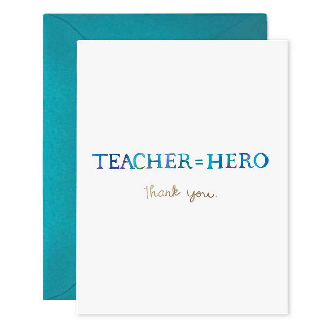 The E. FRANCES PAPER - TEACHER EQUALS HERO CARD by E. FRANCES PAPER is a white card with "TEACHER=HERO" in bold iridescent blue and "thank you" elegantly scripted in gold, made of luxe heavyweight paper. It exudes positivity and includes a matching teal envelope.