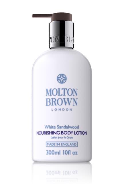 A white bottle of MOLTON BROWN - WHITE SANDALWOOD BODY LOTION with a pump dispenser. The label indicates it features a White Sandalwood floral scent, made in England, and has a volume of 300ml or 10 fl oz.