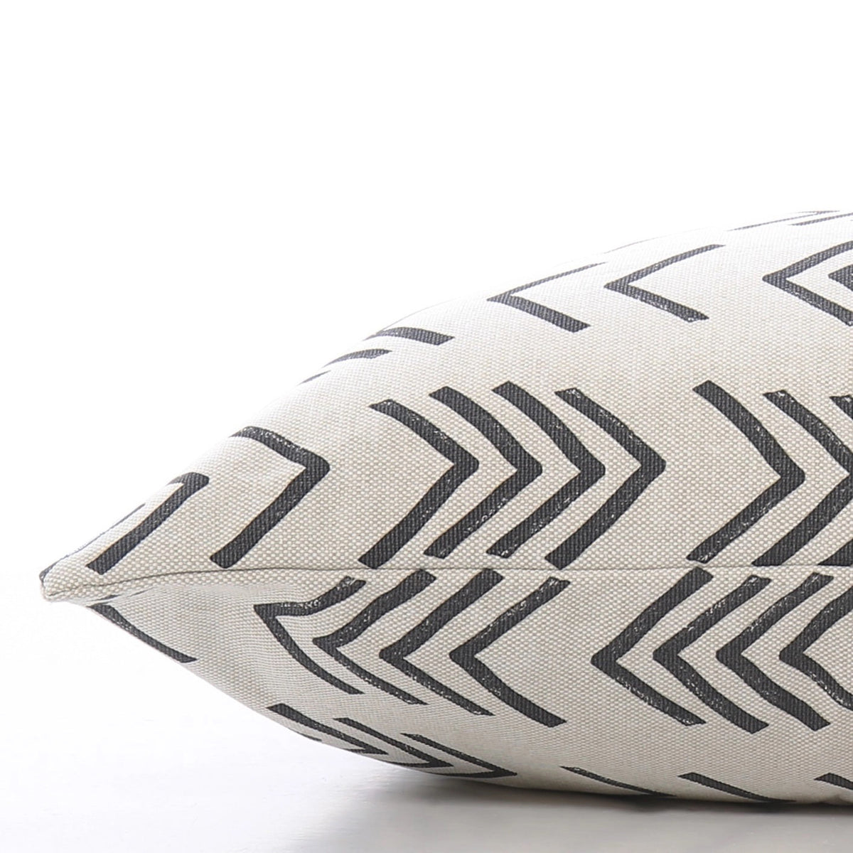 A close-up view of THE FOGGY DOG&#39;s DOG BED (S, MODERN MUD CLOTH), showcasing its cream-colored fabric adorned with black, overlapping chevron lines. This boho minimalist dog bed is lying on its side against a plain, white background.