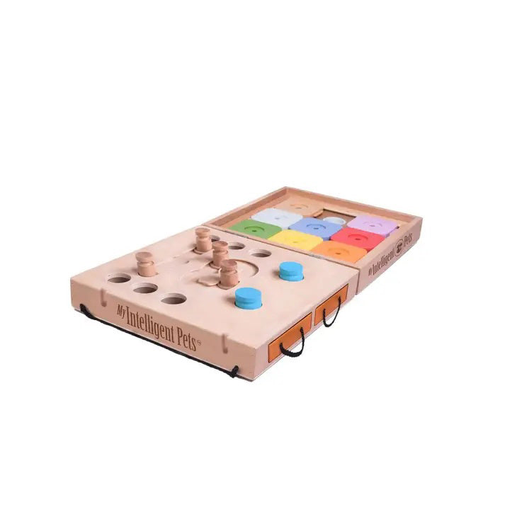 The Dog Travel Puzzle 2 in 1, a pet puzzle toy from &quot;My Intelligent Pets,&quot; features a rectangular wooden board with multiple shaped holes, pegs, and sliders. It uses blue and tan pieces and has compartments for treats or challenges to engage your pet companion in mental stimulation activities.