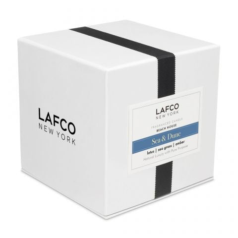 The LAFCO - SEA DUNE, BEACH HOUSE 6.5oz votive candle holder is displayed against a plain white background. Featuring a clear cylindrical design with a white inner surface, this sleek and minimalistic piece evokes the tranquil decor of a beach house, casting a subtle shadow to the right.