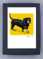 The PAPER RUSSELLS DACHSHUND BOXED CARDS feature an illustration of a black Dachshund with a brown snout and paws on a bright yellow background. The artwork is bordered in white, set on a gray mat, and printed with renewable electricity for sustainability.