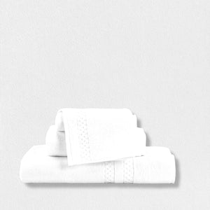 A neatly folded set of the Frette North America FEARRINGTON LIFESTYLE TOWEL COLLECTION - WASH CLOTH, made from 100% plush cotton, is stacked against a white background. These wash cloths, inspired by the elegance of Fearrington House Inn, feature a subtle decorative band pattern and vary in size. The overall aesthetic is clean, simple, and minimalist.