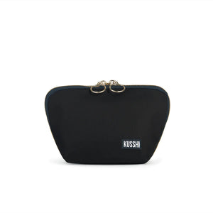 The KUSSHI - Everyday Makeup Bag Black is a stylish black makeup bag adorned with gold accents and the "KUSSHI" logo on the bottom right corner. It features two zipper pulls at the top and is designed to be machine washable for easy care.