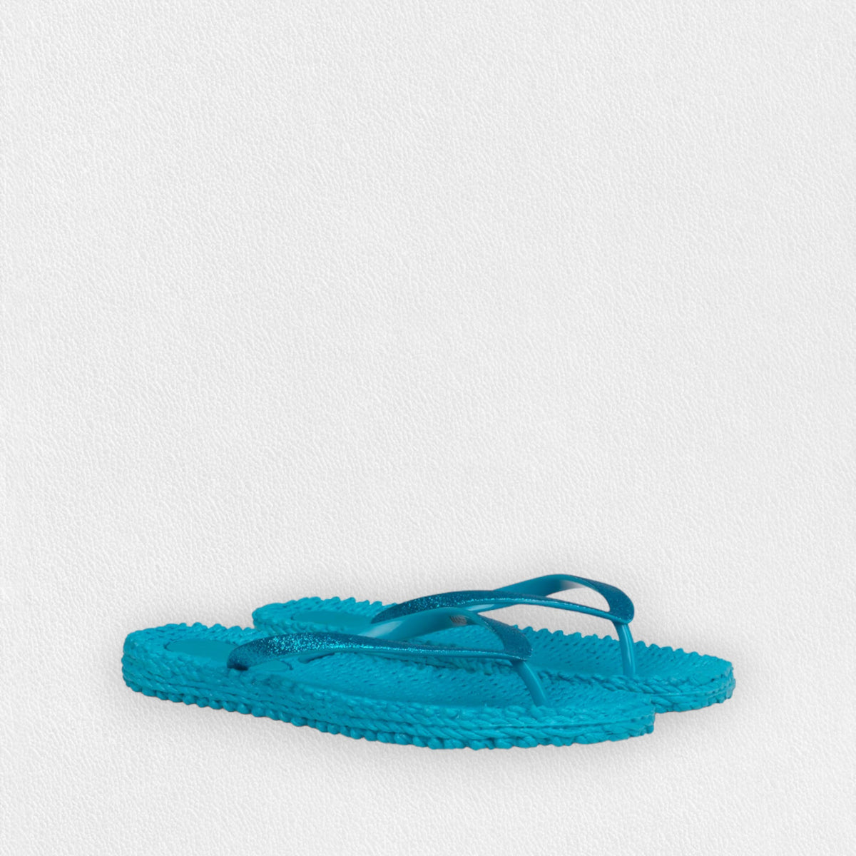 A pair of ILSE JACOBSEN - Cheerful Flip Flops in Veridian Green with textured soles and thin straps is placed against a plain white background. Known for their comfortable fit, the flip-flops by Lines of Denmark are slightly overlapping, with one tilted on top of the other.