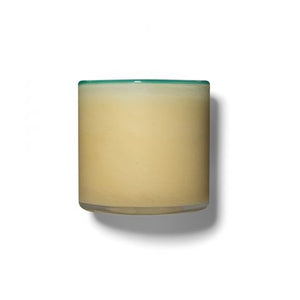 A 6.5 oz LAFCO - French Lilac, Poolhouse candle is displayed in a cylindrical glass container filled with a beige substance. The container features a subtle greenish tint at the rim, evocative of French lilac, and casts a shadow to the right, suggesting the light source is on the left. The background is plain white.