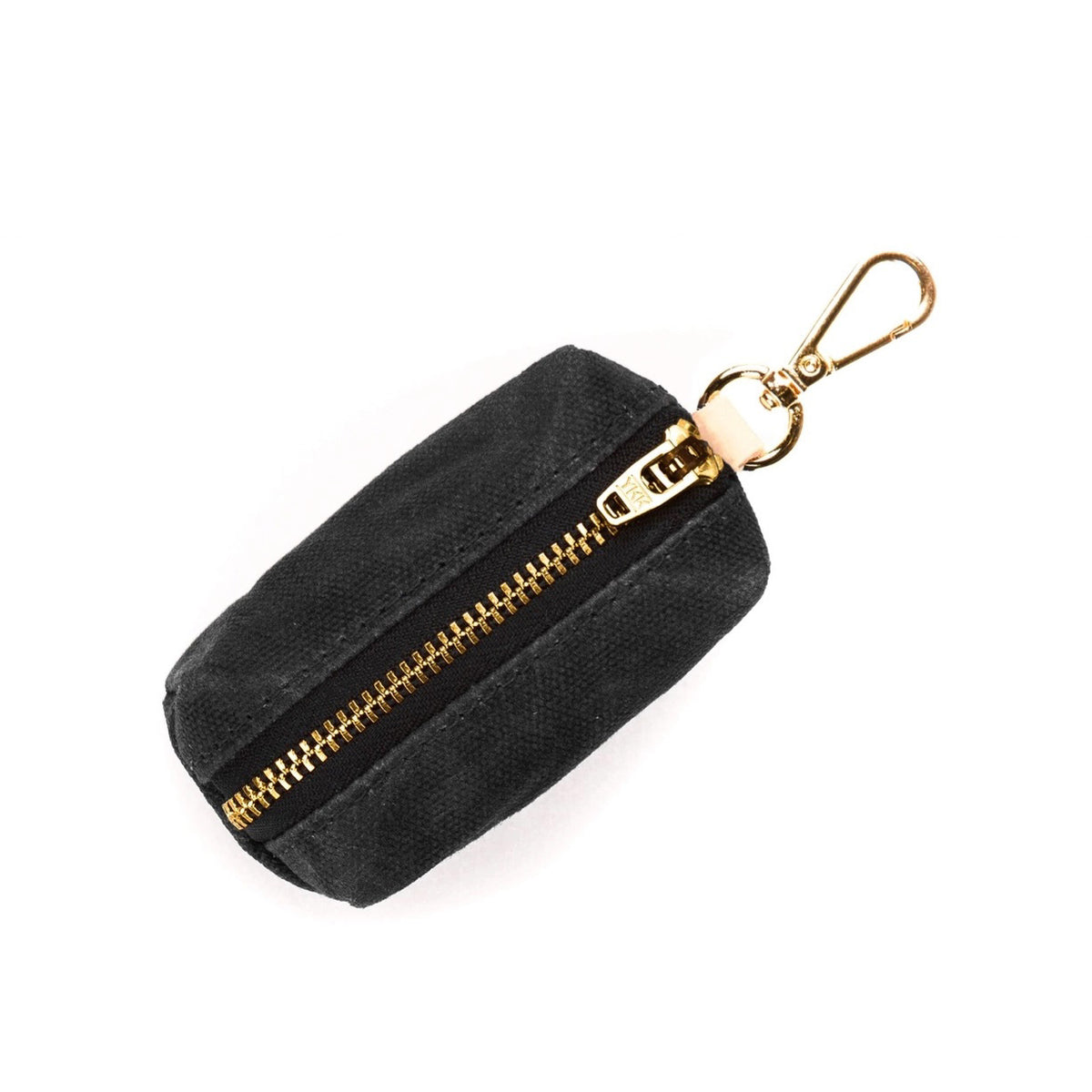 The WASTE BAG DISPENSER (ONYX) by THE FOGGY DOG is a small, black waxed canvas keychain pouch featuring a central gold zipper and a gold clip attachment at the top. The clip allows for easy attachment to bags or belts. Perfect as a poop bag holder, this rectangular pouch with rounded corners is displayed on a white background.