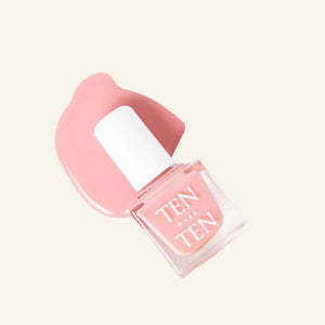 A glass bottle of TENOVERTEN - NAIL POLISH from the brand TEN OVER TEN, featuring a white cap and a dusty pink nail color. The front label displays "TEN OVER TEN" in white uppercase letters. This vegan, eight-free formula ensures both beauty and peace of mind. The background is plain and light-colored.
