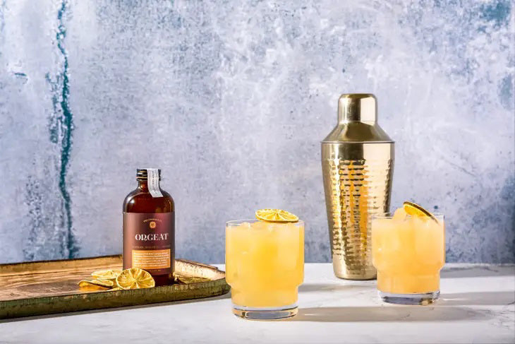 A dark amber glass bottle with a black cap labeled "YES OCKTAIL CO - ORGEAT SYRUP" by YES COCKTAIL CO. This exquisite cocktail syrup highlights almond, marzipan, and orange flavors. The 8 fl oz (237 ml) bottle embodies artisanal quality and balance in every drop.