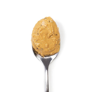 A jar of Big Spoon Roasters Wag Butter Coconut Chia is displayed. This handcrafted nut butter, featuring a gold lid and a green label, showcases the brand name, product name, and various details about the contents and company. This canine superfood is made with care for your furry friend.