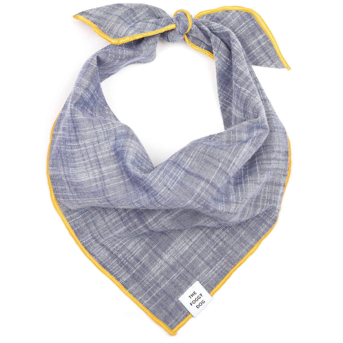 The BANDANA by THE FOGGY DOG is a handmade accessory from San Francisco, featuring a blue and gray checkered pattern with yellow piping around the edges. It can be tied in a knot at the top and includes a small white label at the bottom corner that reads &quot;THE FOGGY DOG.