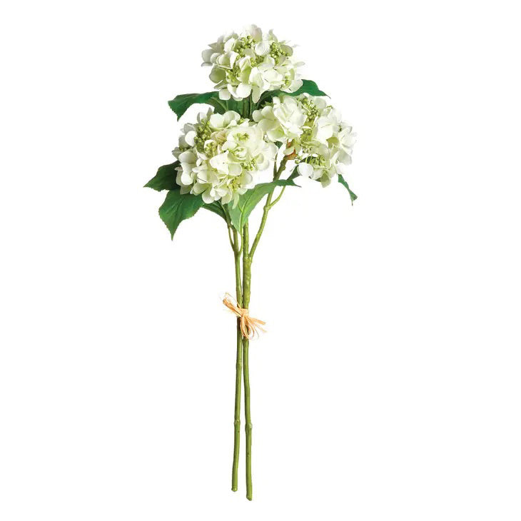 A pair of realistic artificial white hydrangea stems from Napa Home and Garden, featuring lush green leaves and tied with natural string, is shown against a plain white background.