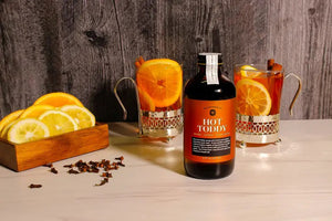 An 8 fl oz (237 ml) brown glass bottle labeled "YES COCKTAIL CO - HOT TODDY SYRUP" from YES COCKTAIL CO., featuring the description "Honey, Lemon, Warm Spice" below. The label promises a warming seasonal drink, perfect for cozy winter nights.