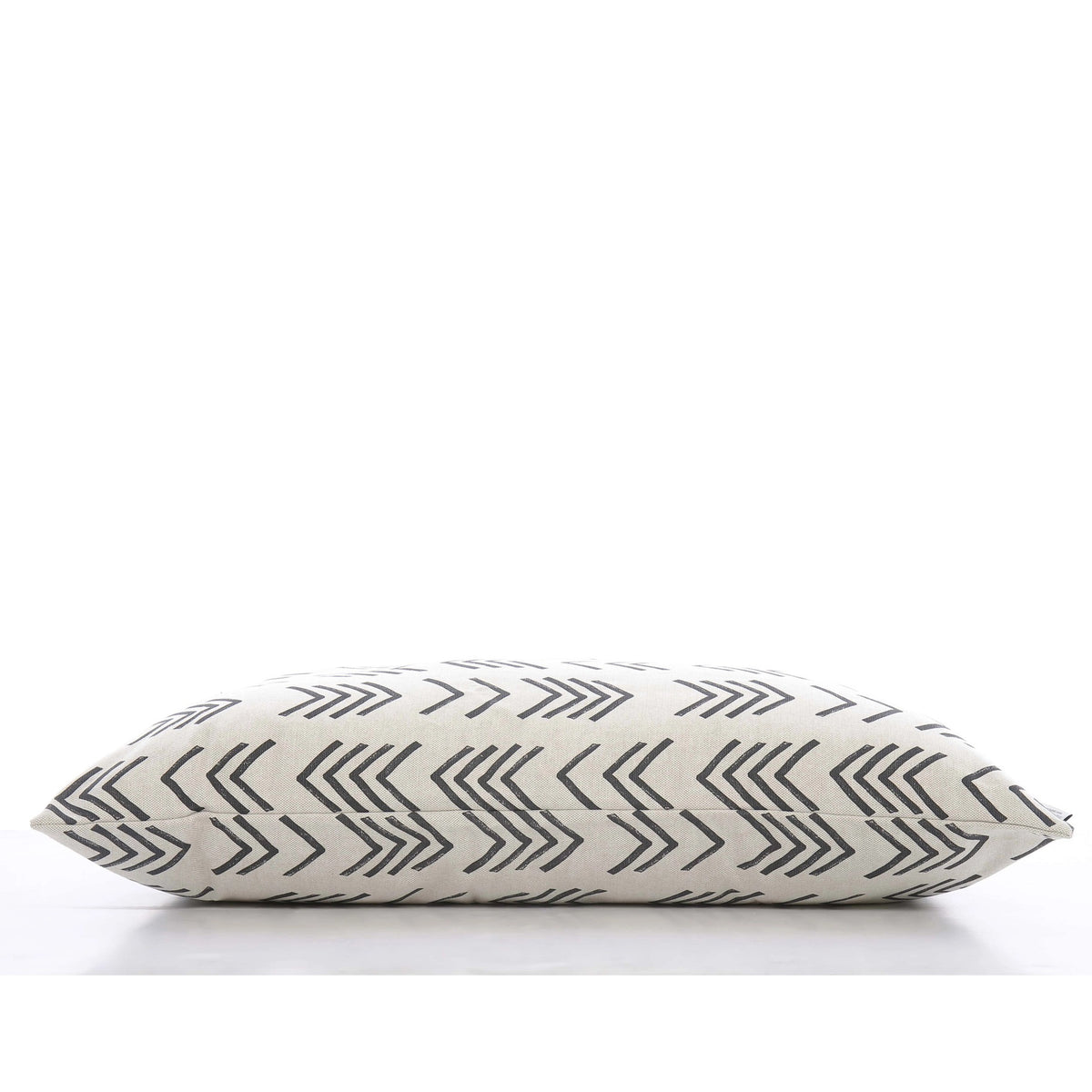 A close-up view of THE FOGGY DOG&#39;s DOG BED (S, MODERN MUD CLOTH), showcasing its cream-colored fabric adorned with black, overlapping chevron lines. This boho minimalist dog bed is lying on its side against a plain, white background.