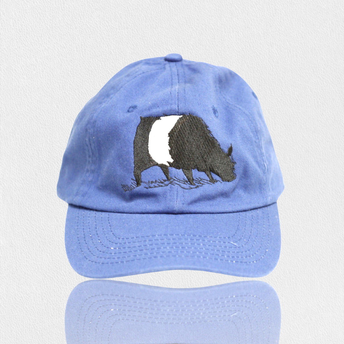The FEARRINGTON LIFESTYLE COLLECTION - YOUTH BELTIE TWILL HAT from VALUCAP THREDS is a blue cotton twill baseball cap featuring an embroidered black and white badger on the front. This premium fabric cap has a curved brim and is displayed against a plain, white background.