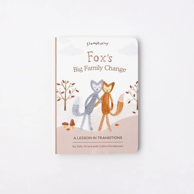 Cover of the SLUMBERKINS - FOX BIG FAMILY CHANGE BOOK by Kelly Oriard with Callie Christensen. The illustration features two anthropomorphic foxes embracing in a fall-themed environment with trees, capturing heartfelt emotions. The subtitle reads "A Lesson in Transitions".