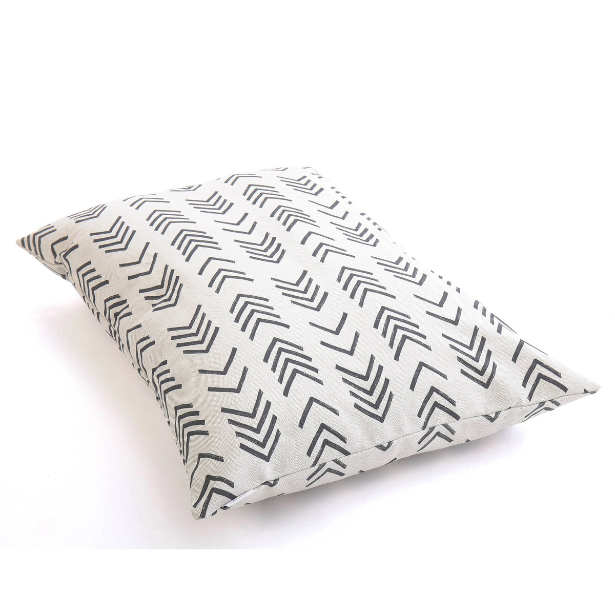 A close-up view of THE FOGGY DOG&#39;s DOG BED (S, MODERN MUD CLOTH), showcasing its cream-colored fabric adorned with black, overlapping chevron lines. This boho minimalist dog bed is lying on its side against a plain, white background.