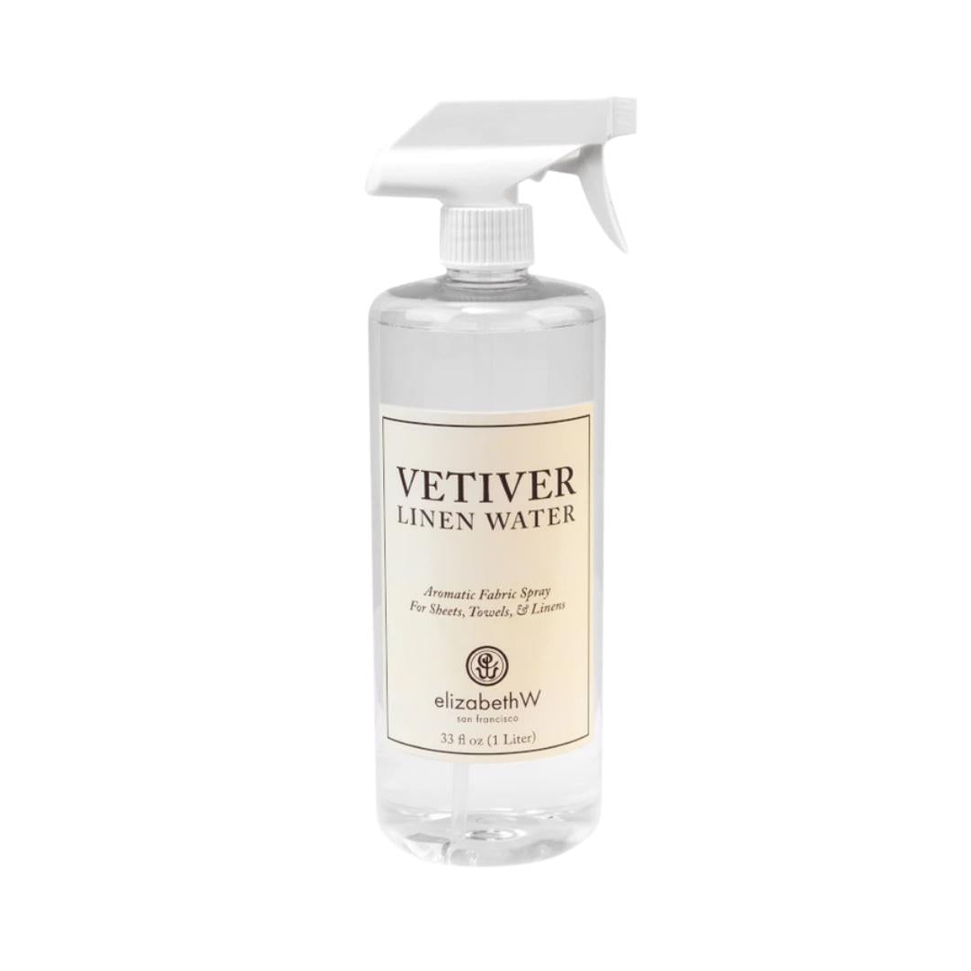 A clear spray bottle labeled &quot;Vetiver Linen Water&quot; with a white trigger nozzle. The label includes the brand name &quot;E Wightman &amp; Co&quot; and describes it as a freshly scented aromatic fabric spray for sheets, towels, and linens in a 1-liter (33 fl oz) container.