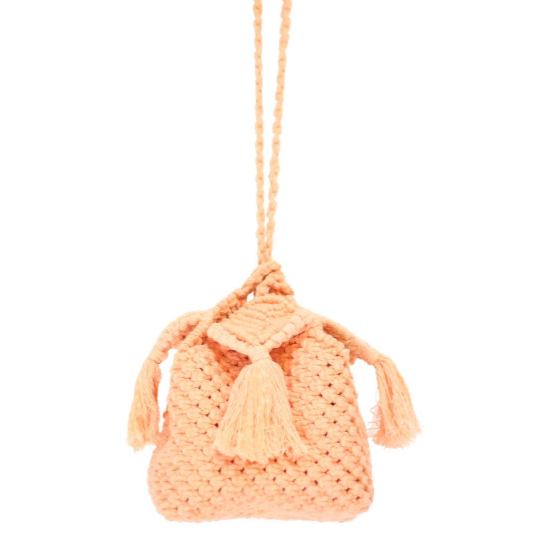An orange drawstring pouch made of knit fabric hangs against a white background. Handcrafted by artisans, the PANDORA PEONY BOX BAG by BRUNNA CO features braided strings, a small flap on top, and two tassels that dangle from either side, embodying the essence of sustainable fashion accessories.