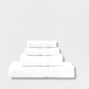 A set of four neatly stacked towels from the FEARRINGTON LIFESTYLE TOWEL COLLECTION by Frette North America is displayed against a plain white background. These luxurious white cotton bath towels are adorned with a textured band across the width, adding an elegant design element to the plush linens.