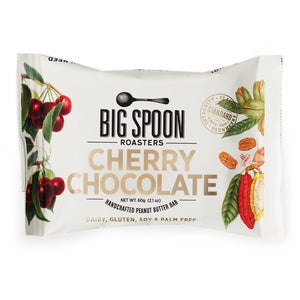 The BIG SPOON ROASTERS - CHERRY CHOCOLATE PEANUT SNACK BAR features a white wrapper with illustrations of cherries, organic dark chocolate cocoa pods, and leaves, plus product details and nut butter ingredient highlights on the front.