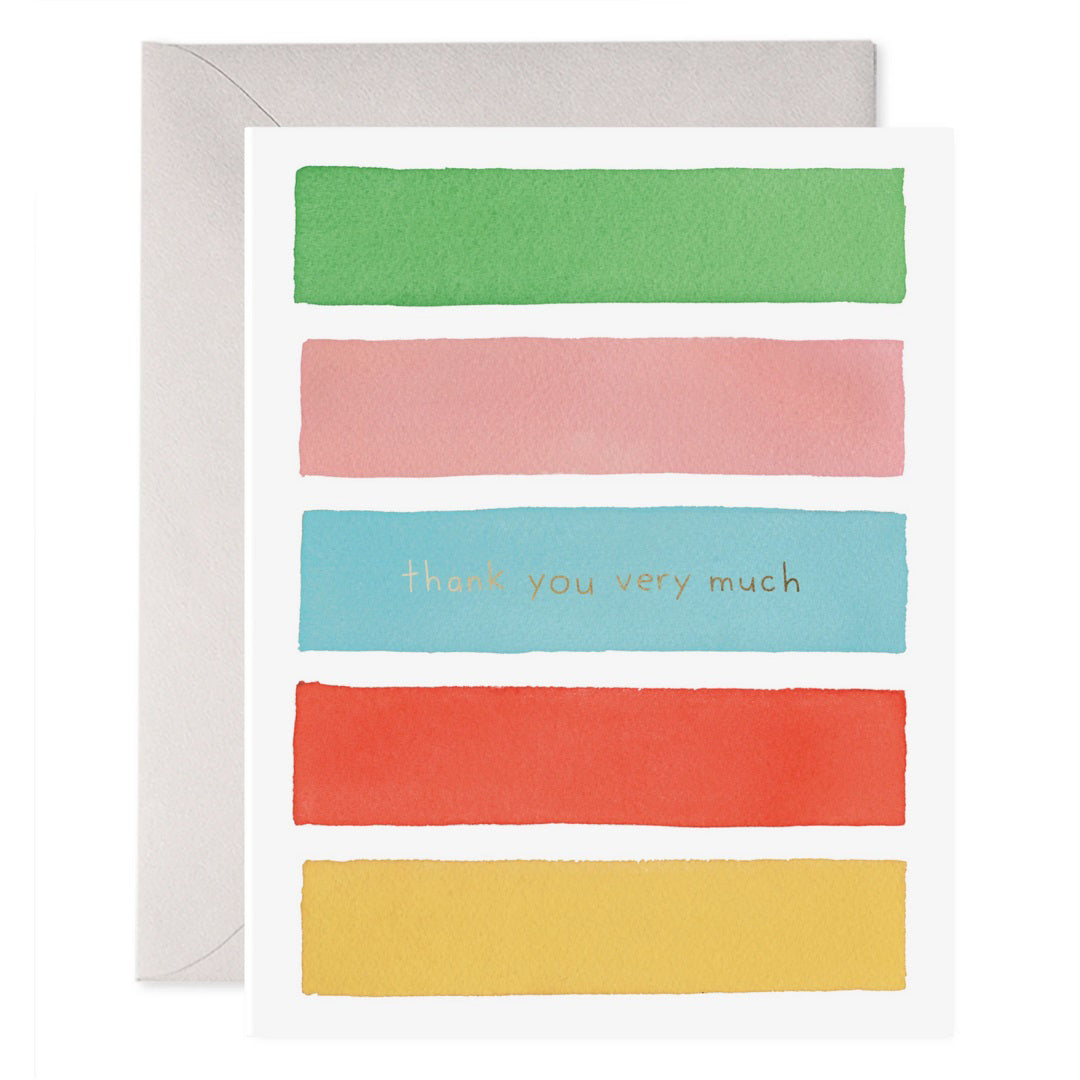 The E. FRANCES PAPER - COLOR BARS THANK YOU CARD showcases five horizontal watercolor stripes in green, pink, blue, red, and yellow. The words "thank you very much" shimmer with gold foil on the blue stripe and come elegantly placed on an envelope.