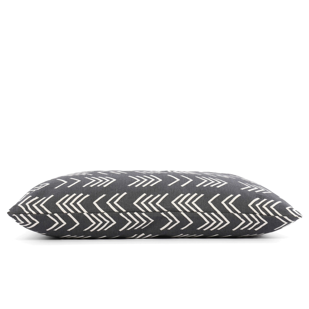 Close-up of The Foggy Dog&#39;s DOG BED (S, MODERN MUD CLOTH BLACK) with a dark gray background and white geometric arrow patterns. The fabric texture is visible, and the pillow is positioned at an angle, showcasing the stitching. Made in the USA with an eco-friendly insert, this boho minimalist dog bed adds style to any space.